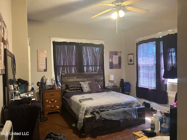 bedroom featuring dark hardwood / wood-style flooring, cooling unit, a textured ceiling, and ceiling fan