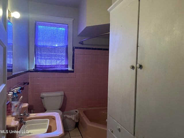 bathroom with toilet, tile patterned floors, sink, and tile walls