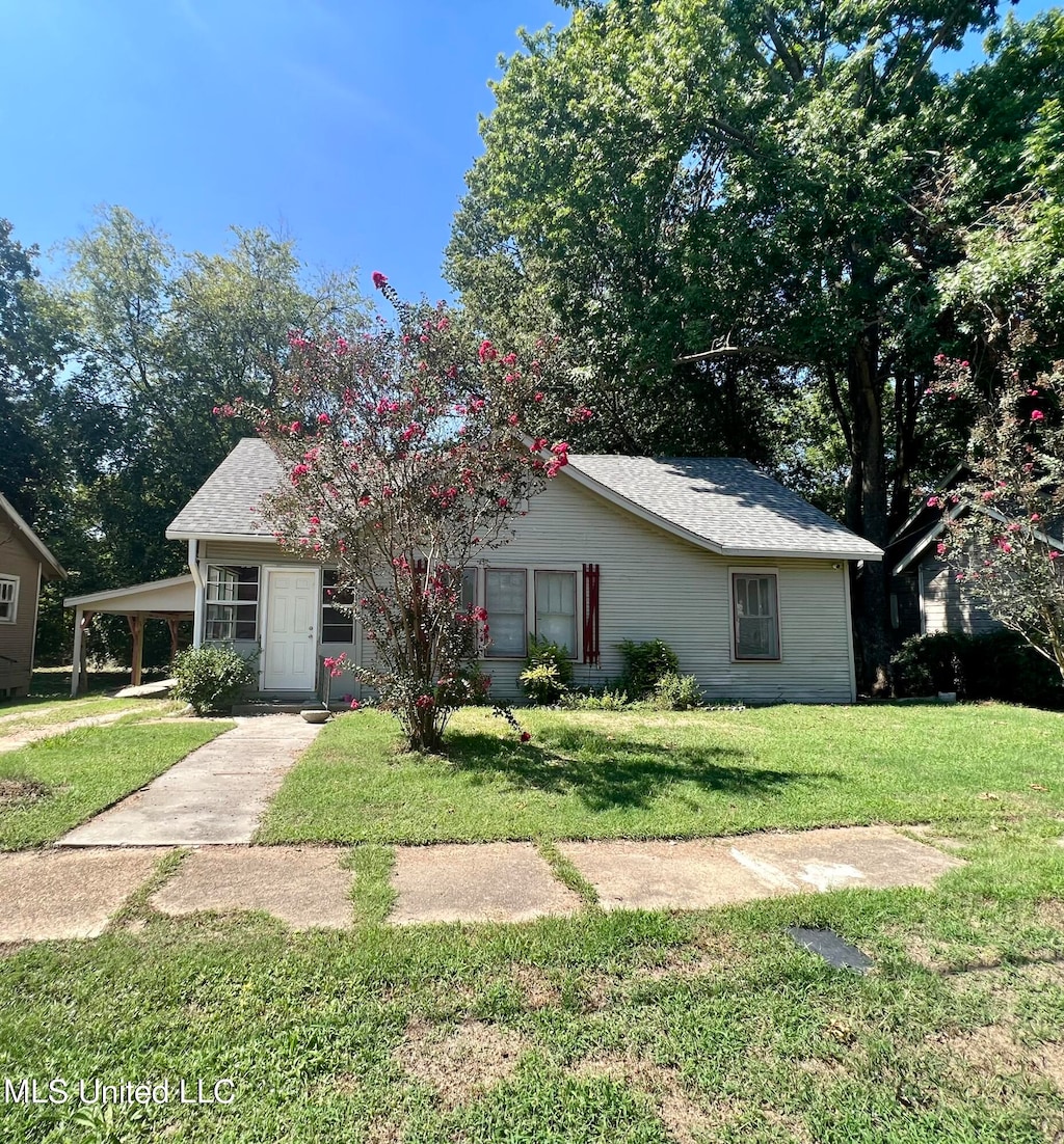 view of front of home with a front yard and a carport