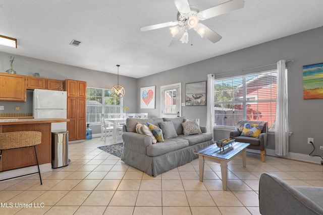 living area featuring visible vents, ceiling fan, a textured ceiling, and light tile patterned floors