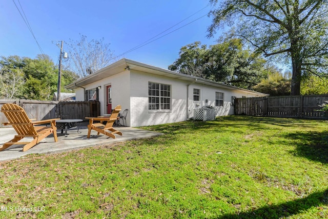 back of house with a patio, brick siding, a lawn, and a fenced backyard