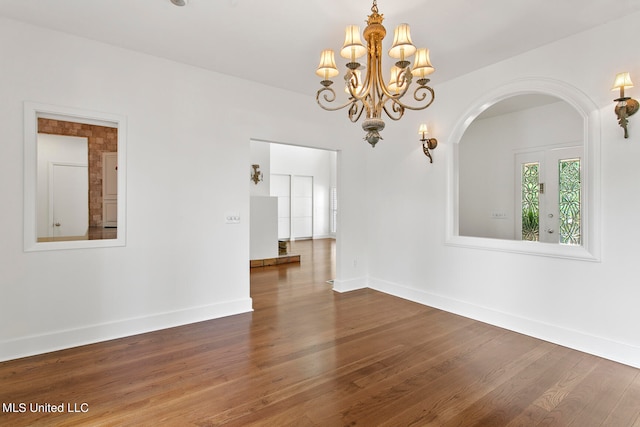 spare room featuring a notable chandelier and dark wood-type flooring