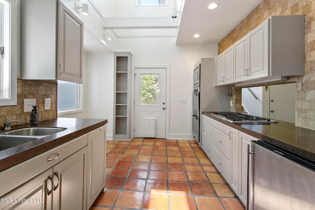 kitchen with decorative backsplash, light tile patterned floors, white cabinetry, sink, and stainless steel appliances