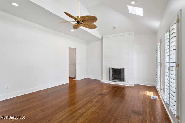 unfurnished living room with ceiling fan, high vaulted ceiling, dark hardwood / wood-style floors, a skylight, and a fireplace