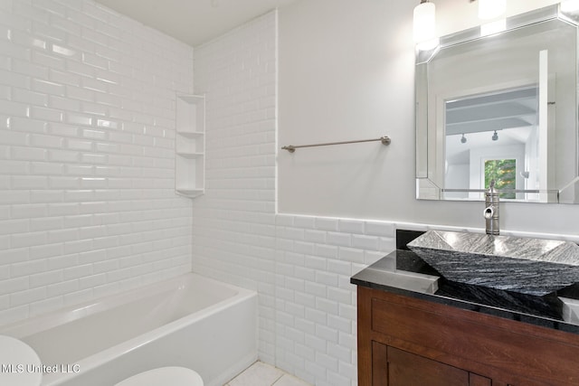 full bathroom featuring toilet, tile patterned flooring, tiled shower / bath, vanity, and tile walls