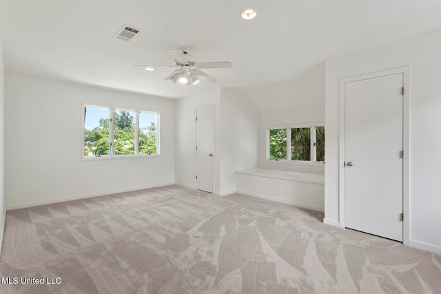 spare room with light carpet, vaulted ceiling, and ceiling fan