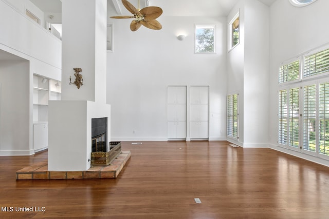 unfurnished living room with ceiling fan, a high ceiling, and dark hardwood / wood-style flooring