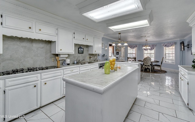 kitchen featuring sink, a kitchen island, crown molding, pendant lighting, and white cabinets