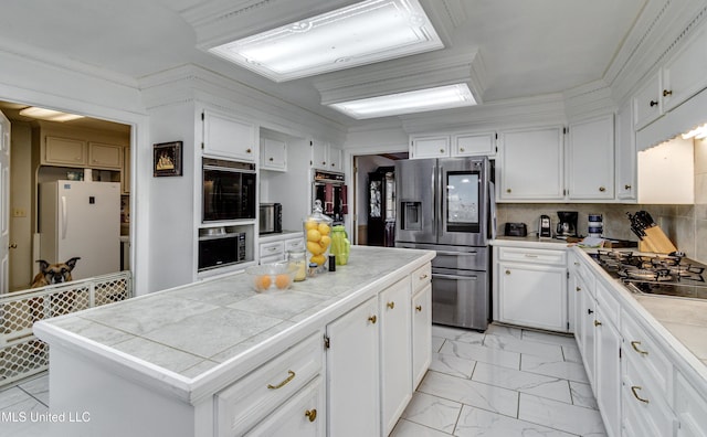 kitchen featuring appliances with stainless steel finishes, tile countertops, white cabinetry, and tasteful backsplash