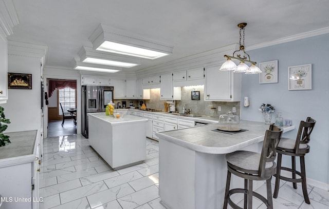 kitchen with white cabinets, pendant lighting, ornamental molding, and kitchen peninsula