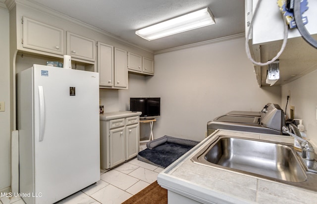 kitchen featuring sink, washing machine and dryer, tile countertops, white fridge, and ornamental molding