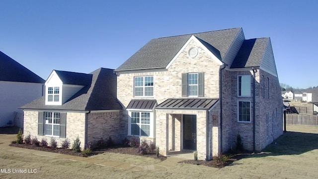 view of front of property with brick siding, a standing seam roof, and a shingled roof