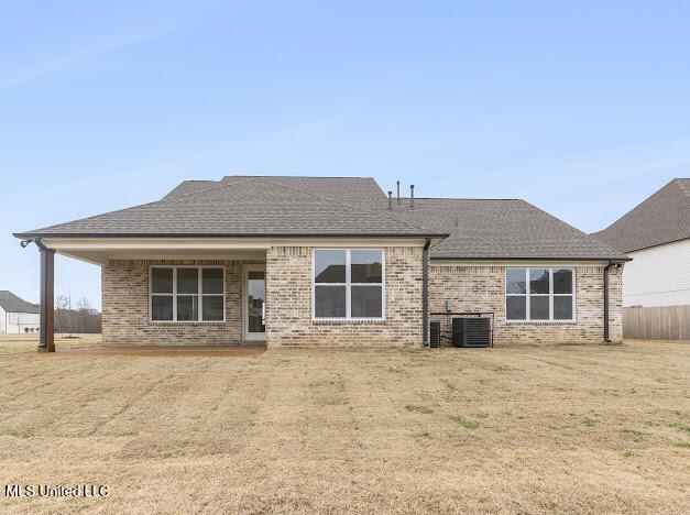 back of property with a yard and central AC