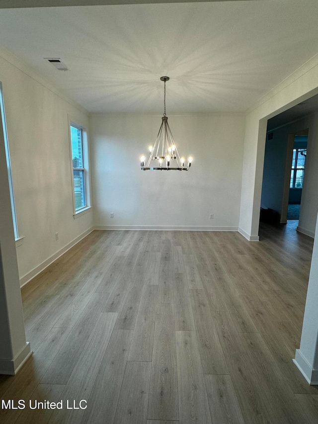 unfurnished dining area featuring an inviting chandelier and hardwood / wood-style floors