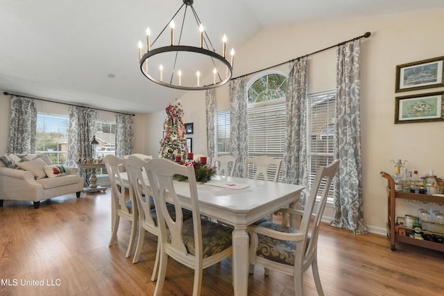 dining room with a chandelier, hardwood / wood-style floors, and vaulted ceiling