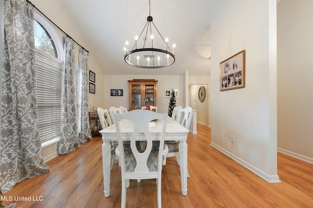 dining space featuring a chandelier, vaulted ceiling, and light hardwood / wood-style flooring