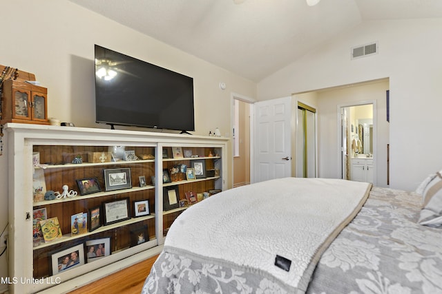 bedroom featuring hardwood / wood-style floors, ensuite bathroom, and vaulted ceiling