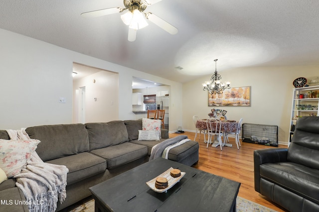 living room featuring a textured ceiling, lofted ceiling, wood-type flooring, and ceiling fan with notable chandelier