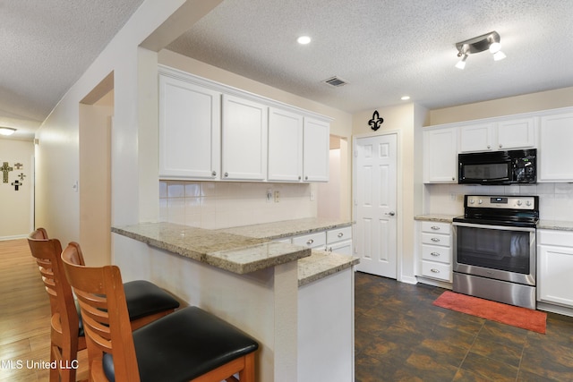 kitchen with tasteful backsplash, white cabinetry, and stainless steel range with electric stovetop