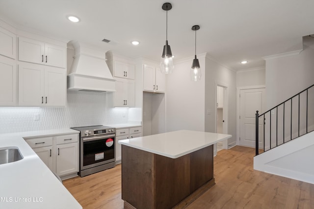 kitchen featuring decorative backsplash, white cabinetry, light wood-type flooring, custom range hood, and stainless steel range with electric stovetop