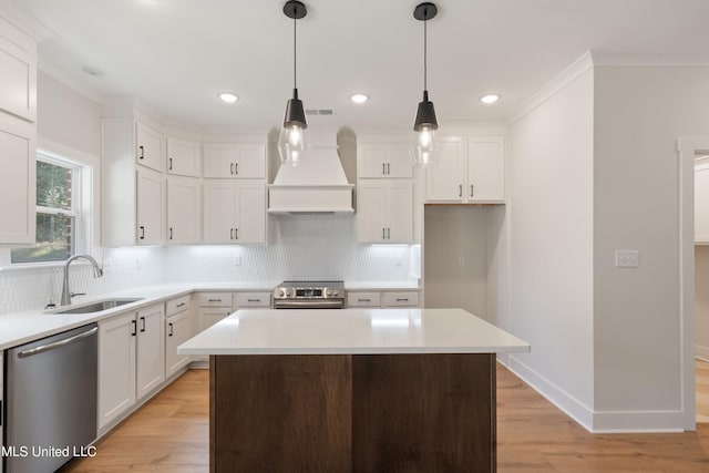 kitchen with a kitchen island, sink, white cabinetry, appliances with stainless steel finishes, and light hardwood / wood-style floors