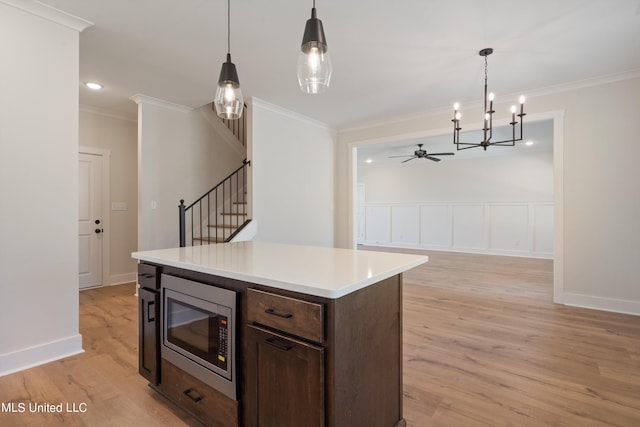 kitchen featuring light hardwood / wood-style floors, stainless steel microwave, and hanging light fixtures