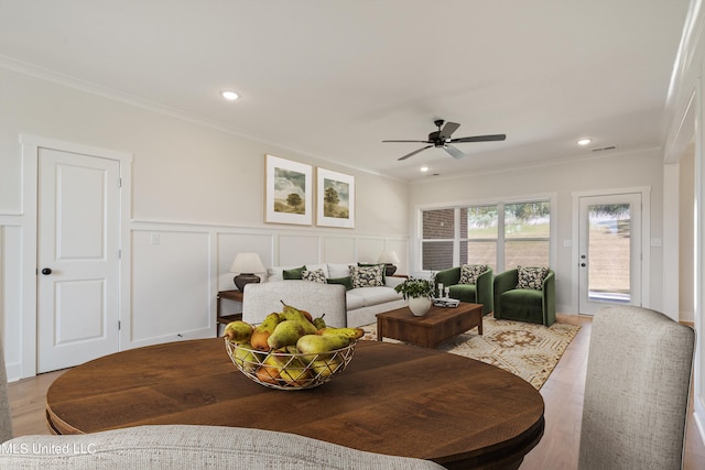 living room featuring ceiling fan, wood-type flooring, and ornamental molding