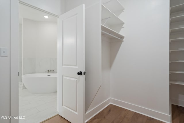 bathroom featuring hardwood / wood-style flooring and a tub to relax in