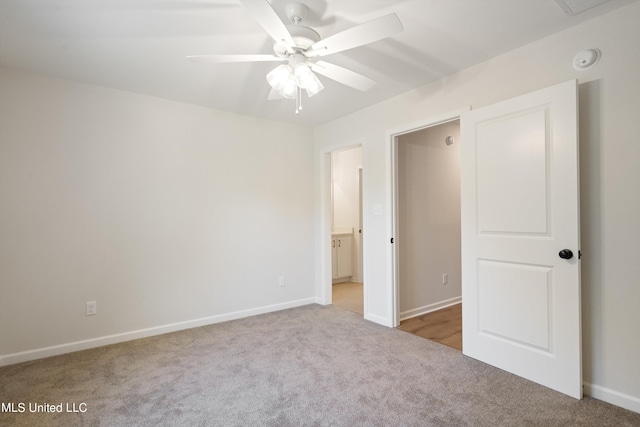 unfurnished bedroom featuring ensuite bathroom, light colored carpet, and ceiling fan