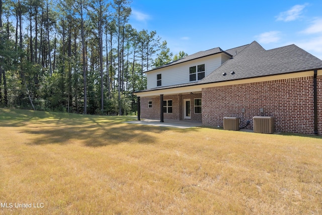 rear view of property with central air condition unit, a patio, and a lawn