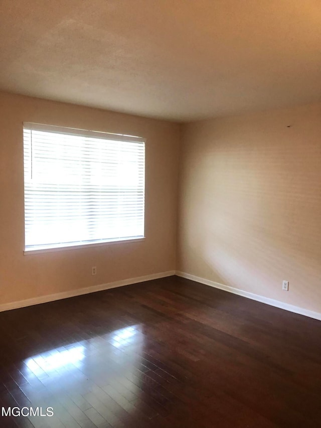 unfurnished room with dark hardwood / wood-style flooring