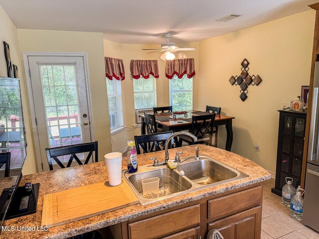 kitchen featuring ceiling fan, sink, light tile patterned floors, and a wealth of natural light