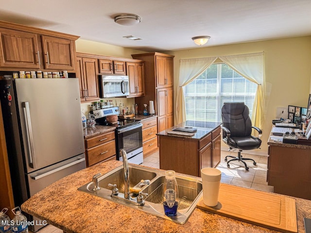 kitchen featuring an island with sink, stainless steel appliances, and light tile patterned flooring