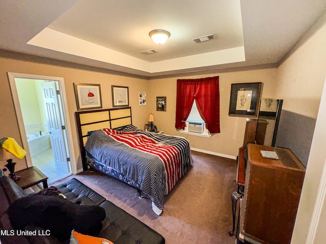 bedroom featuring cooling unit, ensuite bath, a tray ceiling, and dark colored carpet