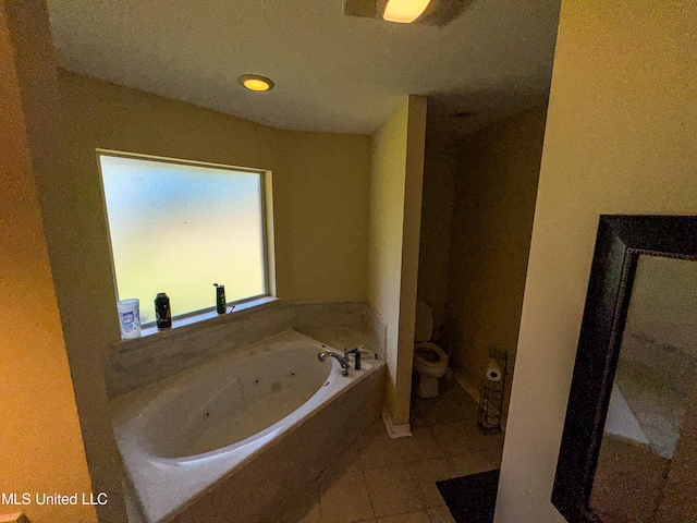 bathroom with a tub to relax in, tile patterned floors, and toilet