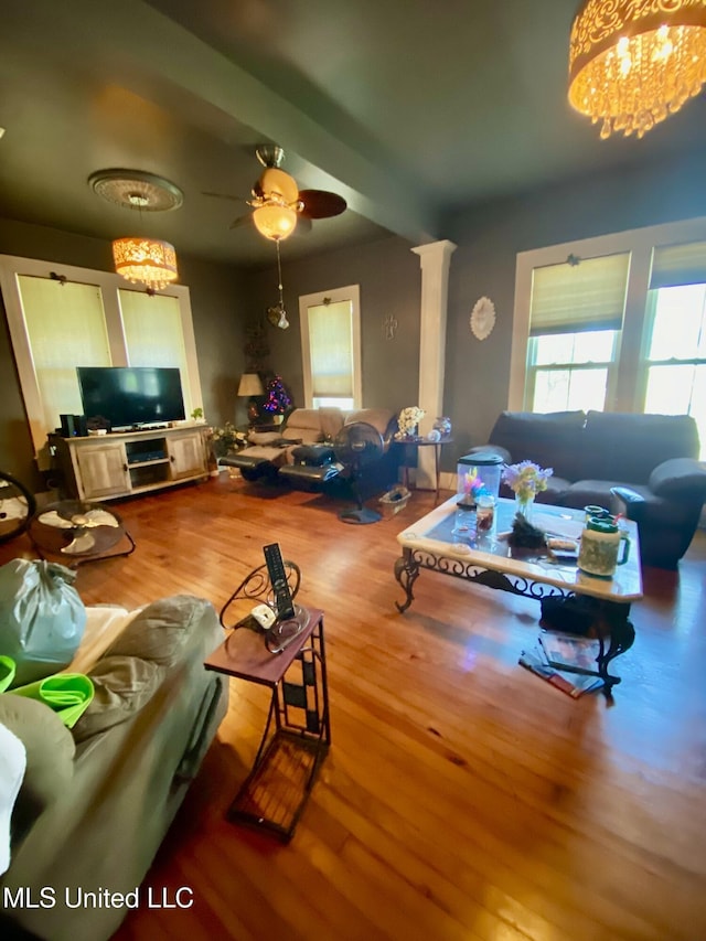 living room featuring ceiling fan with notable chandelier, light hardwood / wood-style floors, and beamed ceiling