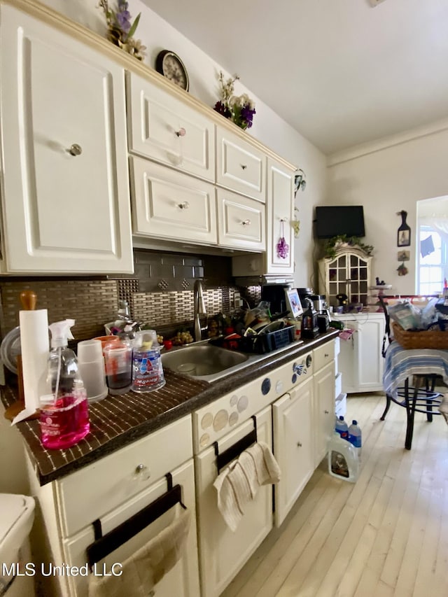 kitchen featuring sink, backsplash, light hardwood / wood-style flooring, and white cabinets