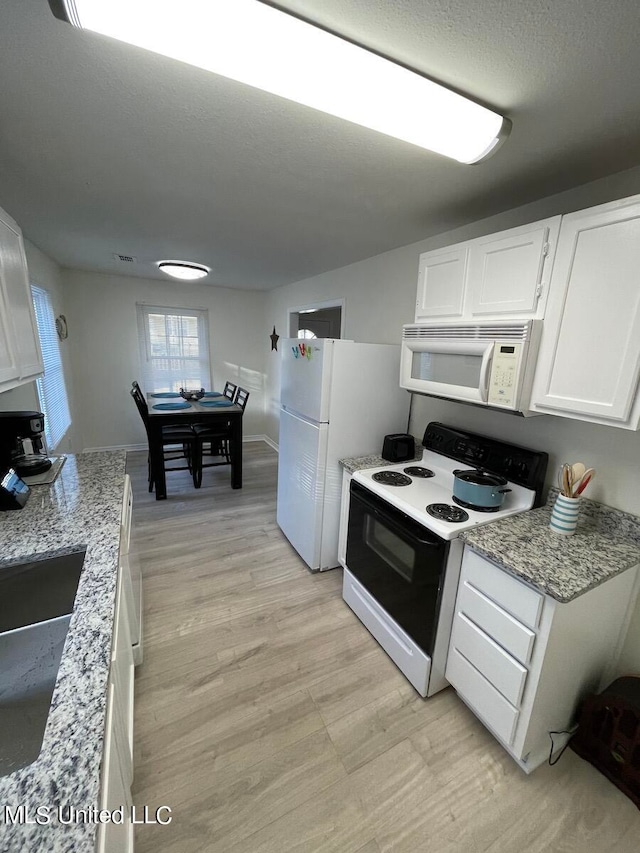 kitchen featuring white cabinets, a textured ceiling, light stone countertops, sink, and white appliances