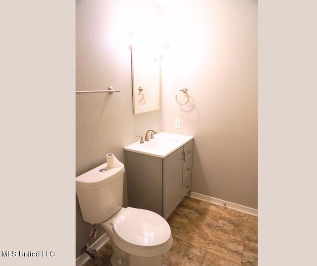 half bathroom featuring toilet, vanity, and baseboards