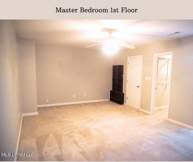 carpeted spare room with visible vents, baseboards, and ceiling fan