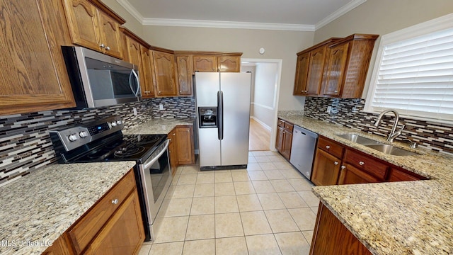 kitchen with appliances with stainless steel finishes, light stone counters, tasteful backsplash, and a sink