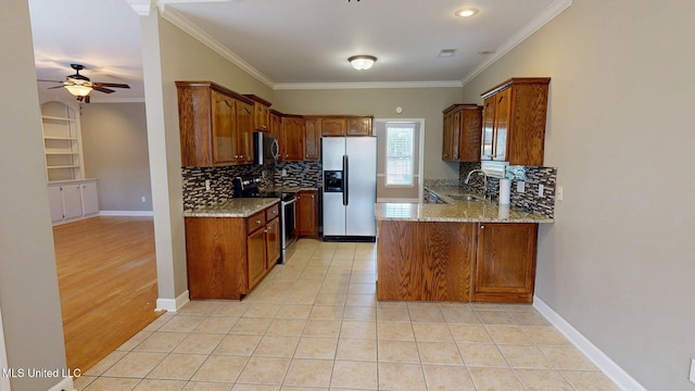 kitchen featuring a ceiling fan, light stone counters, a peninsula, backsplash, and stainless steel appliances