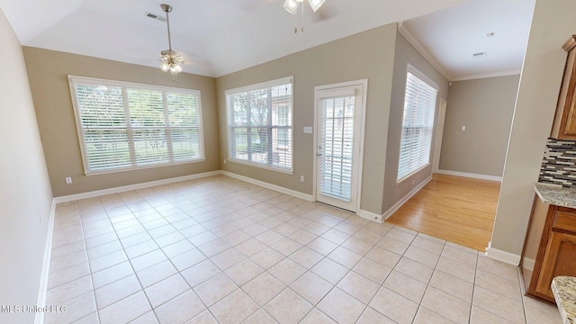 unfurnished dining area featuring light tile patterned flooring, crown molding, a ceiling fan, and a healthy amount of sunlight