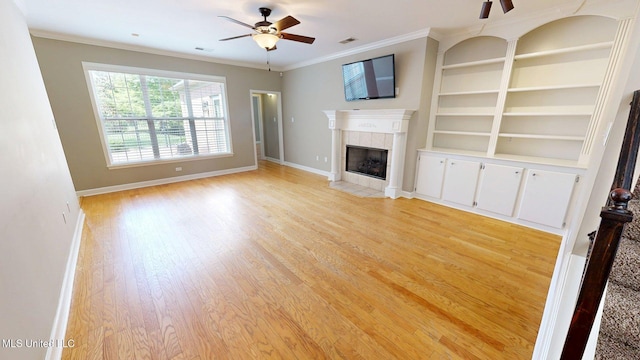 unfurnished living room with a ceiling fan, a tile fireplace, light wood finished floors, baseboards, and ornamental molding