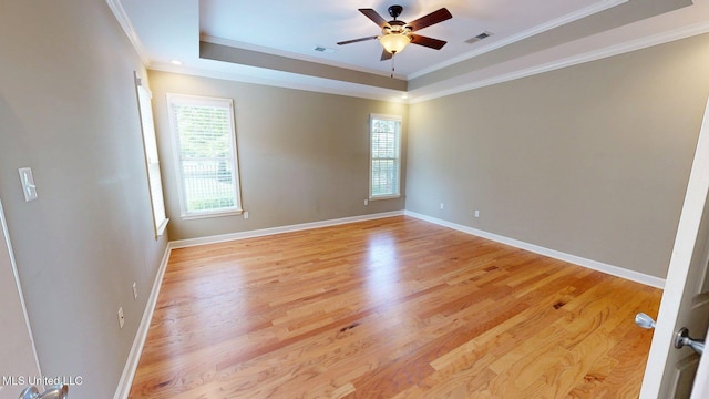 empty room featuring ceiling fan, a raised ceiling, crown molding, and visible vents