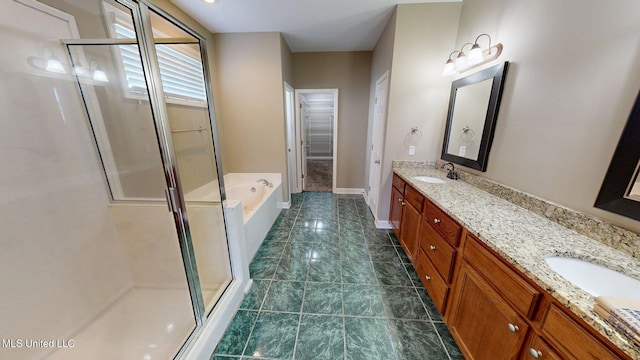 bathroom with a stall shower, double vanity, and a sink