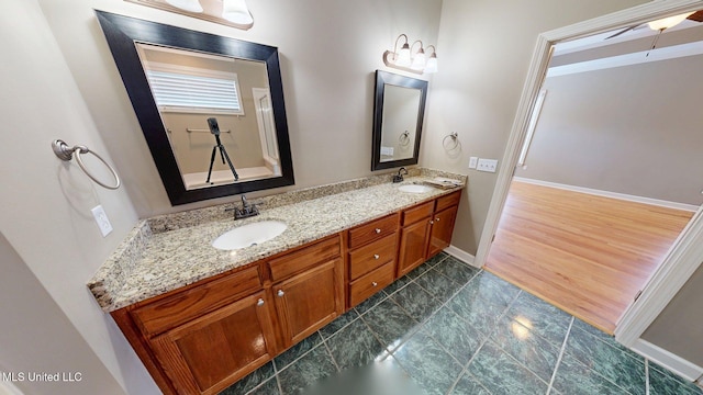 bathroom with double vanity, baseboards, and a sink