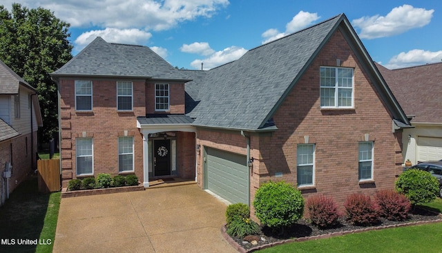 traditional-style home featuring concrete driveway, brick siding, roof with shingles, and fence