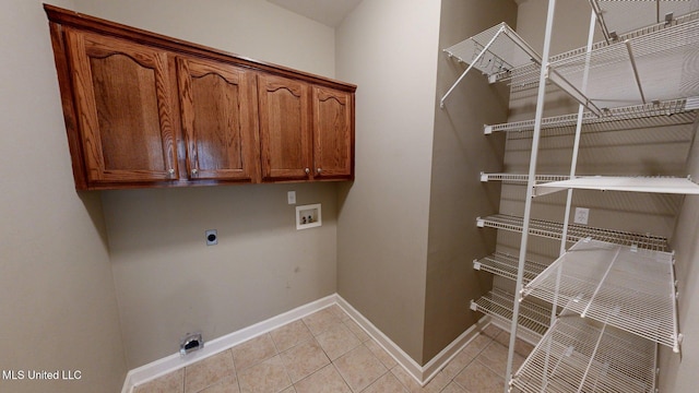 laundry room featuring cabinet space, light tile patterned floors, electric dryer hookup, washer hookup, and baseboards