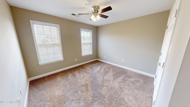 carpeted empty room with visible vents, baseboards, and ceiling fan